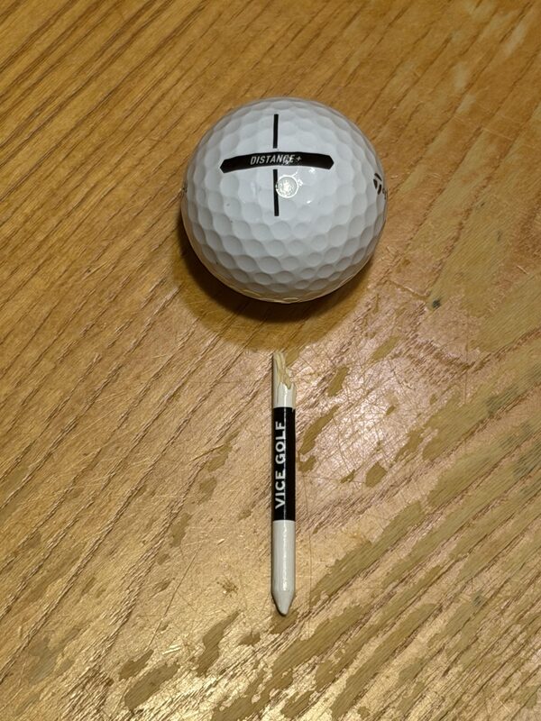 Joseph's split Vice Golf tee — golf ball drilled clean through, tee shattered in half from the impact at distance.